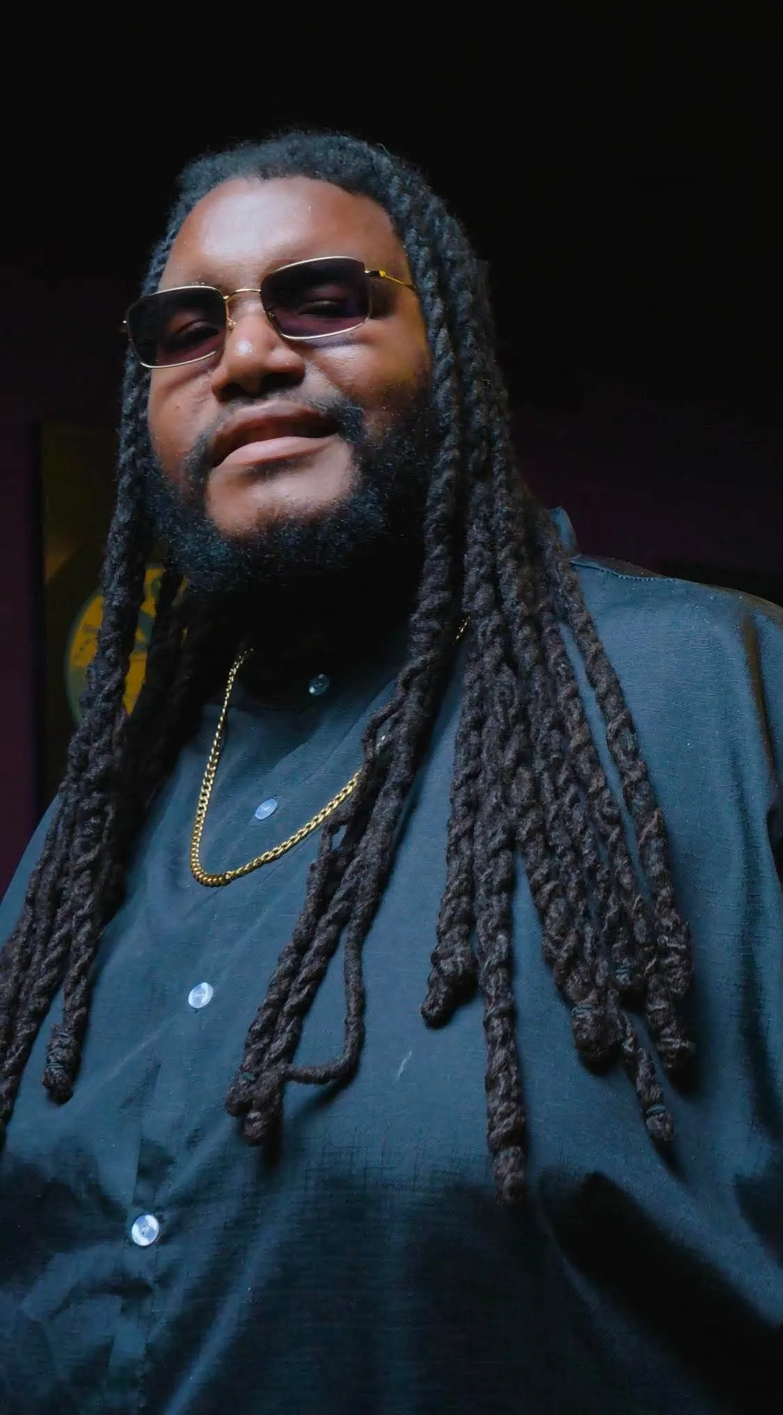 PG Brown in a dark suit and sunglasses, framed by warm stage light